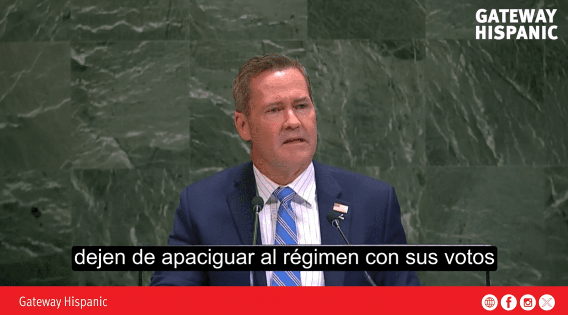 Speaker addressing an audience at a podium, emphasizing political engagement and the importance of voting against oppressive regimes.